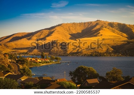 LAKE CHELAN SHORELINE AND ROLLING HILLS WITH A NICE SKY IN LATE SUMMER IN CHELAN WASHINGTON