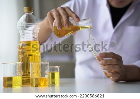 Close up view of industrial worker with vegetable oil quality test in the room.
