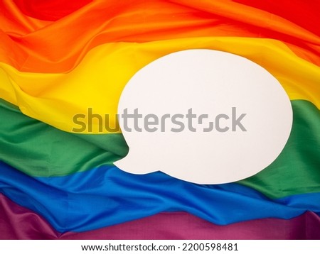 Top view of rainbow flag or LGBT flag with a blank white speech bubble. Close-up photo. Space for text