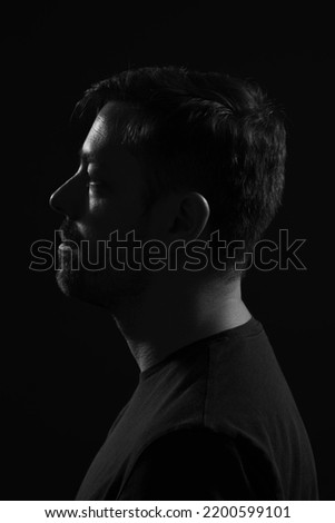 Black and white silhouette portrait of a handsome caucasian male. He is wearing a dark shirt. 