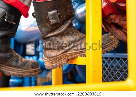 Action of a construction worker is climbing on the platform ladder. An industrial working with unsafe action scene photo, close-up at the safety shoe.