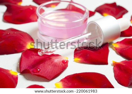 anti aging elixir with a pipette and red rose petals on white wooden