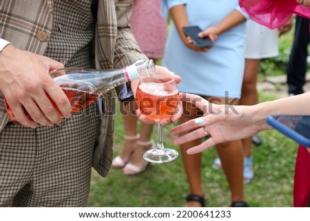 The groom pours a glass of champagne to the wedding guests. Close-up