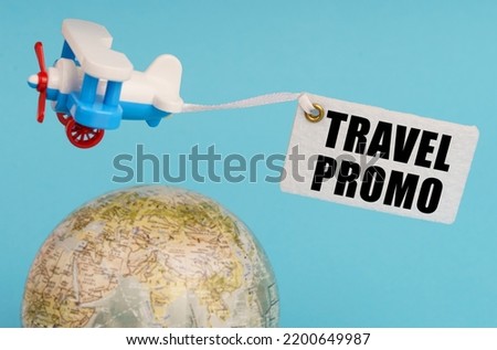Travel and business concept. On a blue background, a globe and an airplane with a sign - Travel promo. Globe out of focus.