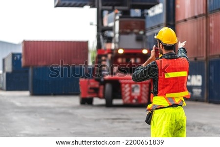 Professional engineer container cargo foreman in helmets working standing and using walkie talkie checking stock into container for loading.logistic transport and business industry export