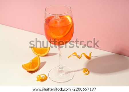 Concept of summer cocktail, Aperol Spritz on white table against pink background Royalty-Free Stock Photo #2200657197