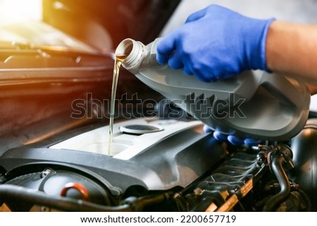 Car oil is pouring into the engine close up. pouring new oil into the engine. automobile engine oil change. vehicle maintenance concept Royalty-Free Stock Photo #2200657719