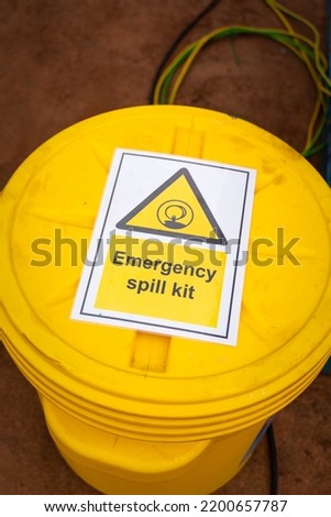 "Emergency spill kit" yellow plastic containment box. Safety sign and symbol at industrial equipment. 