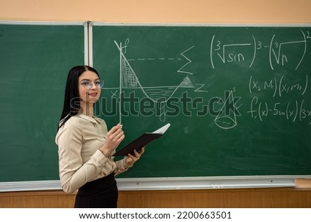 portrait of female student in the classroom near chalkboard. education concept 