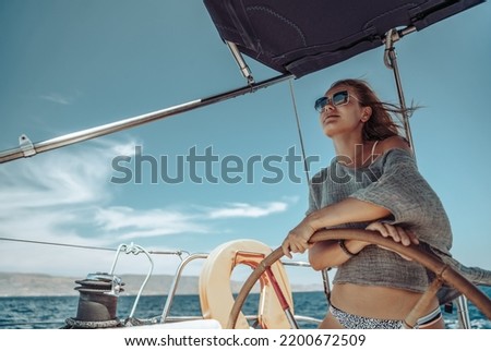 Beautiful Woman on a Helm of a Boat. Having Fun. Enjoying Amazing Sunny Summer Day. Water Sport. Peaceful Vacation. Royalty-Free Stock Photo #2200672509