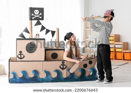 Little boy and his sister dressed as pirates playing with spyglass at home