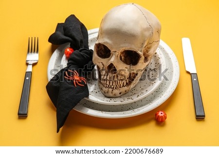 Halloween table setting with scull and spiders on orange background