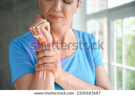 Mature woman having pain in wrist at home Royalty-Free Stock Photo #2200683687