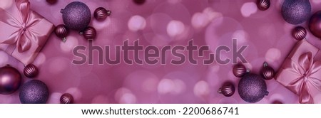 Christmas decorative composition with purple shiny Christmas balls and gift on bokeh lights background. Christmas or New Year concept. Festive Christmas background with baubles and copy space. Banner 
