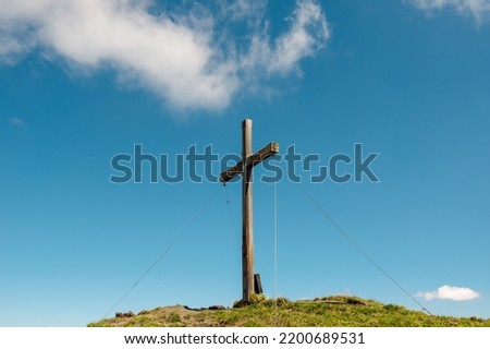 Wooden summit cross in the Austrian mountains, blue sky with white cloud in the background, Kreuzeck summit (2,204 m), Salzburg Land. Royalty-Free Stock Photo #2200689531