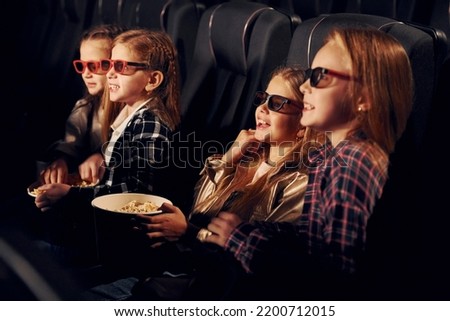 Delicious popcorn. Group of kids sitting in cinema and watching movie together.
