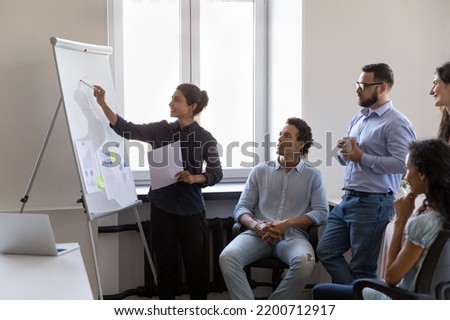 Indian business teacher woman training diverse group of interns, drawing marketing chart on whiteboard, explaining data, teaching students. Multiethnic team leader presenting report Royalty-Free Stock Photo #2200712917