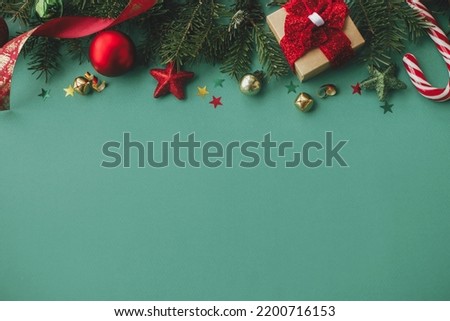 Stylish christmas border with festive decorations, confetti,gift, fir branches on green background. Christmas flat lay. Merry Christmas! Seasons greetings card template, space for text