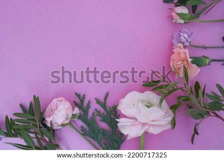 View from above. Part of a close-up frame of fresh flowers rose, ranunculus, carnation, juniper, eustoma, bush chrysanthemum, on a lilac background. With a space to copy. High quality photo