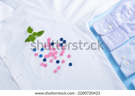 Conscious and environmentally friendly consumption. A green leaf in the pocket and scattered buttons on the background of a white shirt.top view. Slow fashion concept. High quality photo