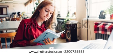 Surprised woman looking her notes with interest, sitting and working in big and bright open space