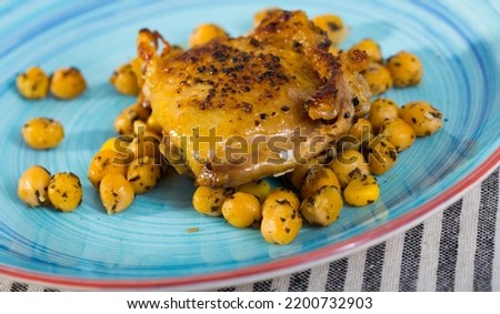 Appetizing fried chicken thighs with spicy stewed chickpeas served on colored platter