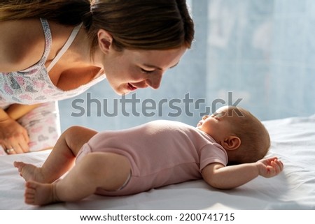 Young beautiful mother with baby on the bed. Family motherhood love concept