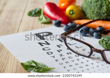 Food for eyes health, colorful vegetables and fruits, rich in lutein, eyeglasses and eye test chart on wooden background, concept Royalty-Free Stock Photo #2200742249