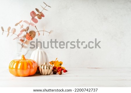 Details of Still life, pumpkins, candle, brunch with leaves on white table background, home decor in a cozy house. Autumn weekend concept. Fallen leaves and home decoration Royalty-Free Stock Photo #2200742737