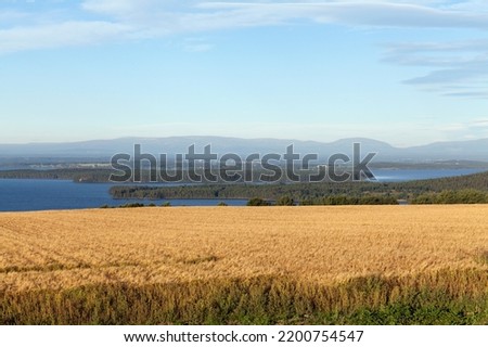 View of the landscape in the Great Lake area, Sweden.  Agriculture, farmland, forests, and water in the morning sun. Mountains in the background. Royalty-Free Stock Photo #2200754547