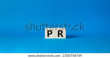 PR - Public Relations symbol. Concept word PR on wooden cubes. Beautiful blue background. Business and PR concept. Copy space.