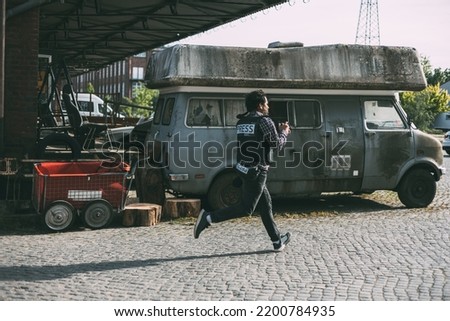 Photojournalist running with camera and helmet Royalty-Free Stock Photo #2200784935