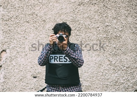 Photojournalist hand holding with camera looking through lens Royalty-Free Stock Photo #2200784937