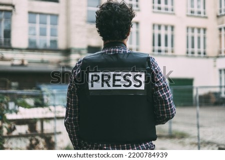 Photojournalist with bulletproof vest on his back Royalty-Free Stock Photo #2200784939