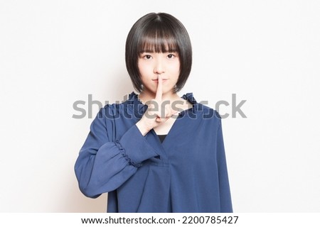 A young woman who hides her mouth with her hand and makes a secret pose