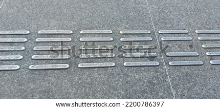 Metal border and sidewalk signs for the blind people on the street