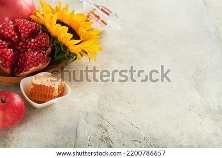 Rosh Hashanah. Ripe pomegranate, apple, honey and sunflower, yellow flowers on rustic grey background. Composition with symbols autumn jewish Rosh Hashanah holiday attributes. Top view with copy space
