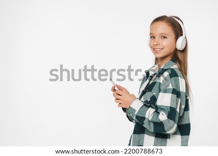 Young caucasian preteen teenager schoolgirl listening to the music podcast soundtrack radio in headphones using mobile application isolated in white background