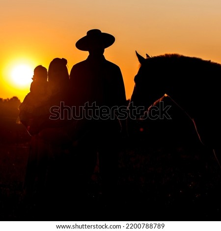 Silhouette of Gaucho family with horse at sunset