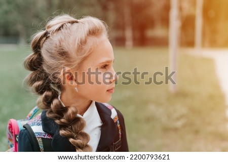 back to school. face portrait little happy kid pupil schoolgirl eight years old in fashion uniform with backpack and hairstyle voluminous braid ready going second grade first day primary school. flare Royalty-Free Stock Photo #2200793621