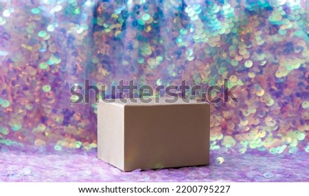 Beautiful iridescent purple color sequins textile background with square shape box pedestal for products. Lot of copy space. Side view. Royalty-Free Stock Photo #2200795227