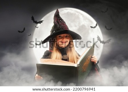charming witch against the background of the moon with a book blonde looks directly into the frame in the smoke on Halloween