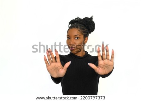 African American woman showing stopping signs. Female model in turtleneck with curly hair looking at camera. Portrait, emotion, studio shot concept