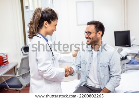 Smiling young female doctor shake hand close health insurance deal with elderly patient at consultation in hospital. Happy woman GP handshake greeting get acquainted with man in clinic. Royalty-Free Stock Photo #2200802265