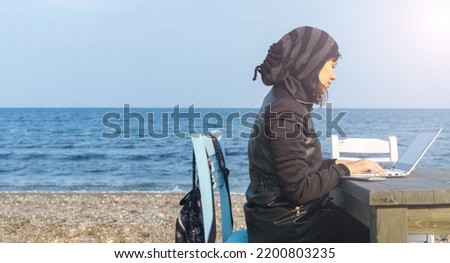 Woman working on laptop on beach. Digital nomadism, remote, freelance working everywhere on sunny day. Large copy space for ad or advertising text. High resolution photo for big display, print, banner