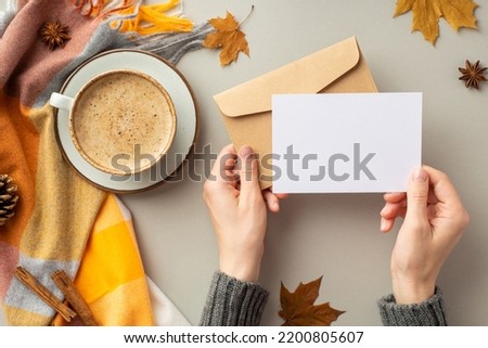 First person top view photo of girl's hands in sweater holding envelope paper card cup of coffee saucer plaid maple leaves pine cone anise cinnamon sticks on isolated grey background with blank space