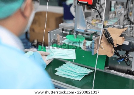 Inspector or worker hands with nitrile gloves doing quality of mask and medical face mask production line, Industry and factory concept.