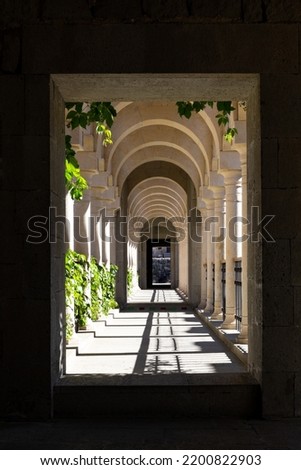 Symmetrical stone passageway with repeating arches, white columns and shadows in the courtyard of Akhaltsikhe (Rabati) Castle, Georgia. Royalty-Free Stock Photo #2200822903