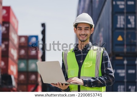 Portrait smart Asian engineer male wearing safety vest and hard helmet hand holding laptop computer standing in front of container box on site Cargo freight ship for import and export. Transport man Royalty-Free Stock Photo #2200853741