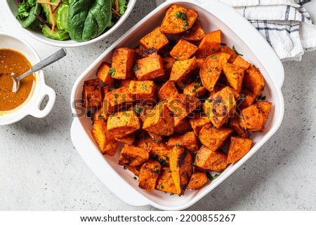 Crispy slices of baked sweet potato with green salad, top view. Vegan food concept. Royalty-Free Stock Photo #2200855267